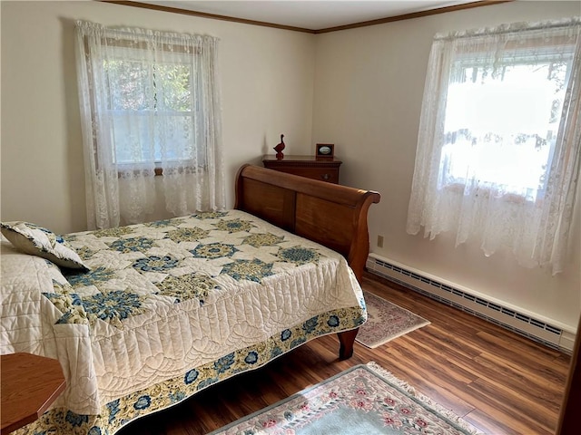 bedroom with ornamental molding, baseboard heating, and wood finished floors