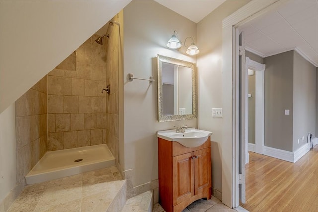full bath with vanity, baseboards, and a tile shower