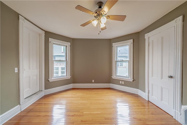 unfurnished bedroom featuring baseboards, light wood-style flooring, and multiple windows