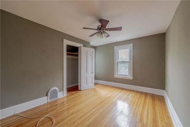 unfurnished bedroom featuring ceiling fan, visible vents, wood finished floors, baseboards, and a closet