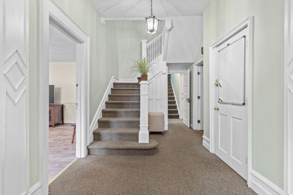 carpeted entrance foyer with baseboards, a notable chandelier, and stairway