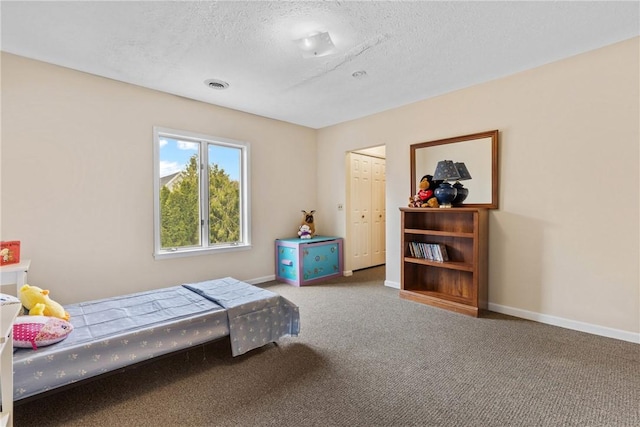 carpeted bedroom with a textured ceiling, baseboards, visible vents, and a closet