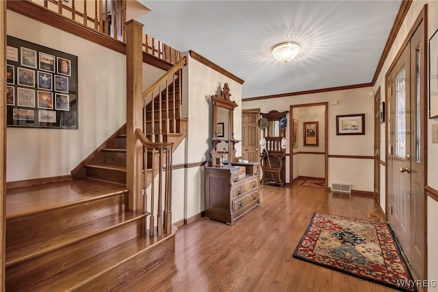foyer entrance with visible vents, baseboards, wood finished floors, and stairway