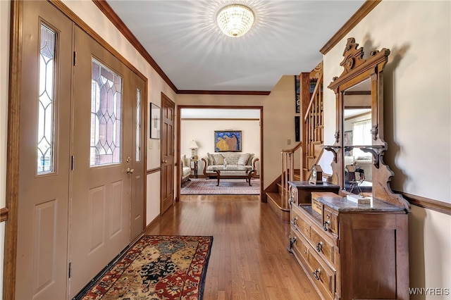 entrance foyer with crown molding, a wealth of natural light, wood finished floors, and stairway