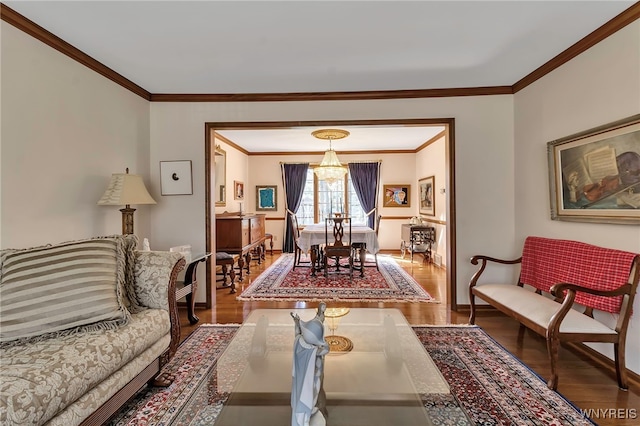 living area featuring a notable chandelier, ornamental molding, and wood finished floors