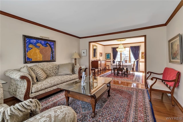 living room with baseboards, crown molding, wood finished floors, and a chandelier