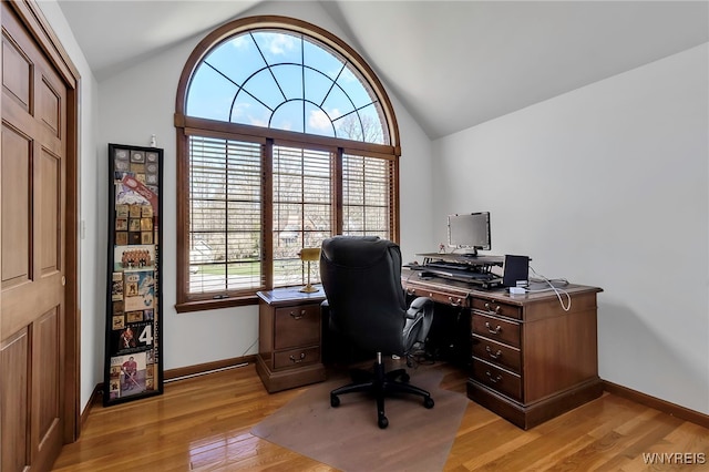 office space with baseboards, vaulted ceiling, and light wood-style floors