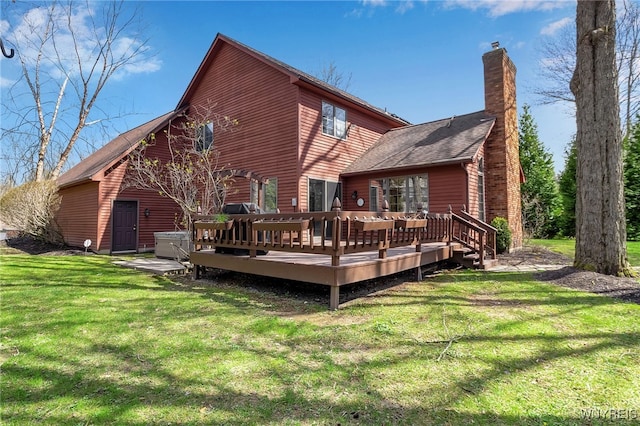 rear view of house with a lawn, a deck, a chimney, and roof with shingles
