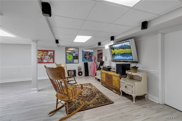 sitting room featuring baseboards, light wood finished floors, and a paneled ceiling