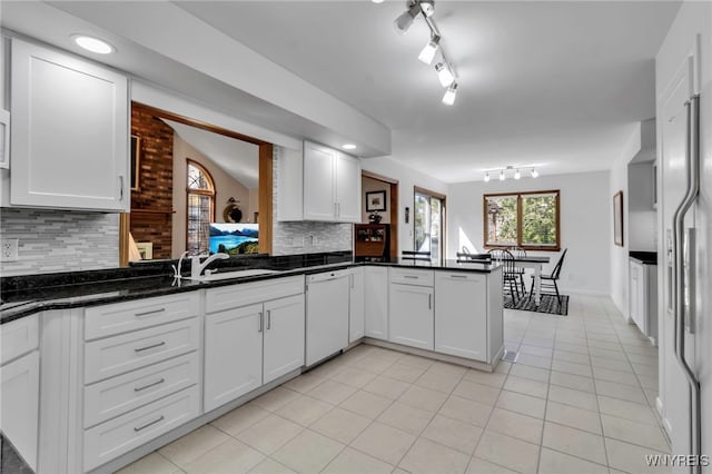 kitchen featuring white appliances, white cabinetry, a peninsula, light tile patterned floors, and backsplash