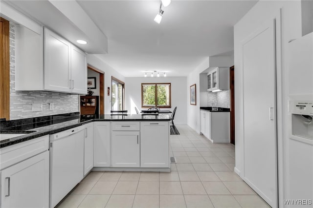 kitchen featuring white cabinets, dishwasher, a peninsula, light tile patterned floors, and tasteful backsplash