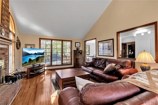living area with high vaulted ceiling, hardwood / wood-style flooring, and a fireplace