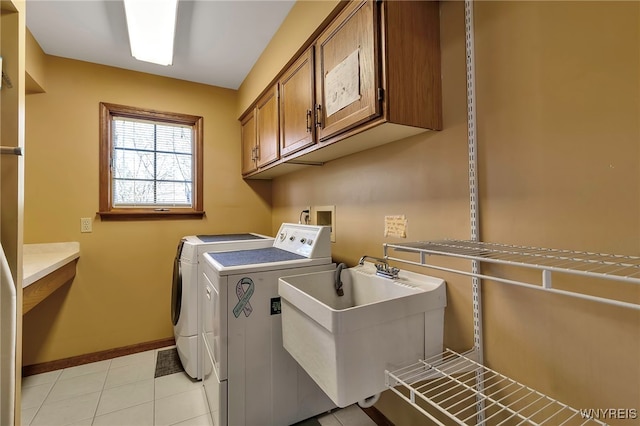 clothes washing area with baseboards, washing machine and clothes dryer, a sink, cabinet space, and light tile patterned floors