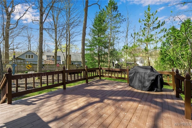 wooden terrace featuring a fenced backyard, grilling area, and a residential view