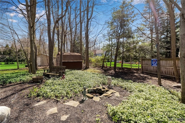 view of yard featuring a shed, an outbuilding, and fence