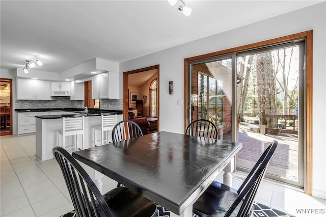 dining space featuring light tile patterned flooring and rail lighting