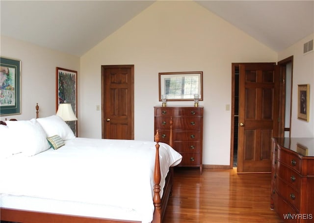 bedroom featuring visible vents, baseboards, wood finished floors, and vaulted ceiling