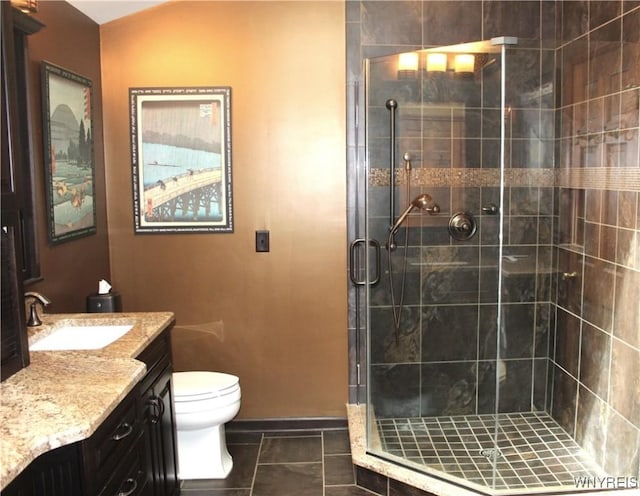 bathroom with vanity, toilet, tile patterned floors, baseboards, and a shower stall