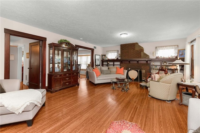 living area featuring a textured ceiling, a brick fireplace, and wood finished floors