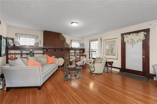 living room with a fireplace, a textured ceiling, and wood finished floors