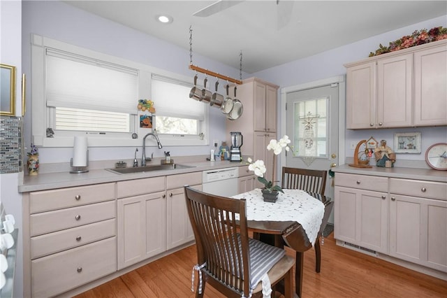 kitchen featuring visible vents, white dishwasher, light countertops, a sink, and light wood finished floors