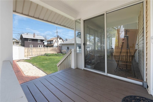 wooden terrace featuring fence, a yard, and a residential view