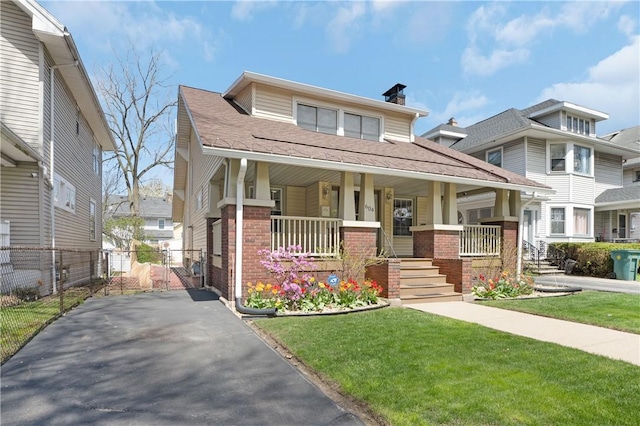 view of front of property with fence, brick siding, a porch, a gate, and a chimney