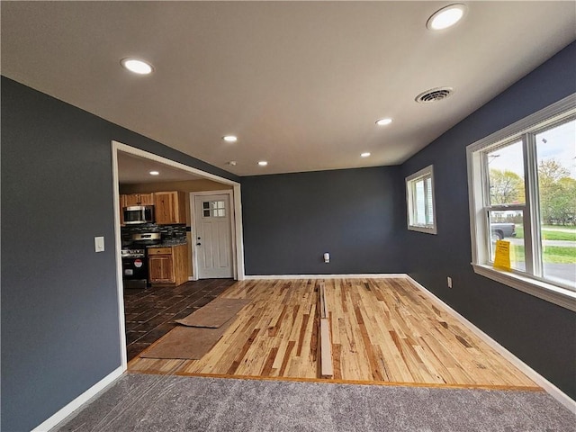 unfurnished living room with recessed lighting, baseboards, visible vents, and dark wood-style floors