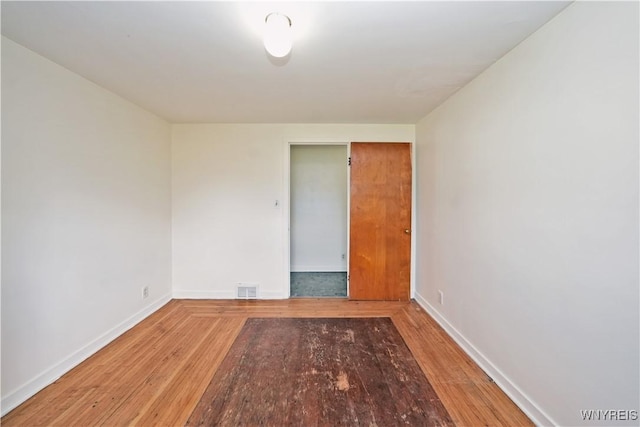 empty room featuring baseboards, visible vents, and wood finished floors