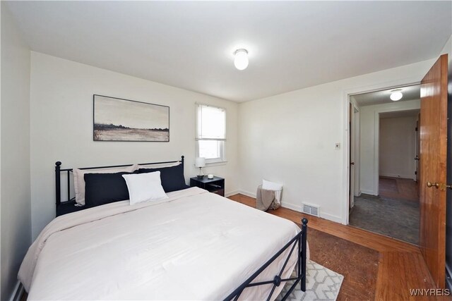 bedroom featuring baseboards, visible vents, and wood finished floors
