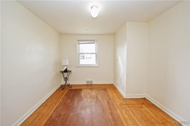 spare room with baseboards, light wood finished floors, and visible vents