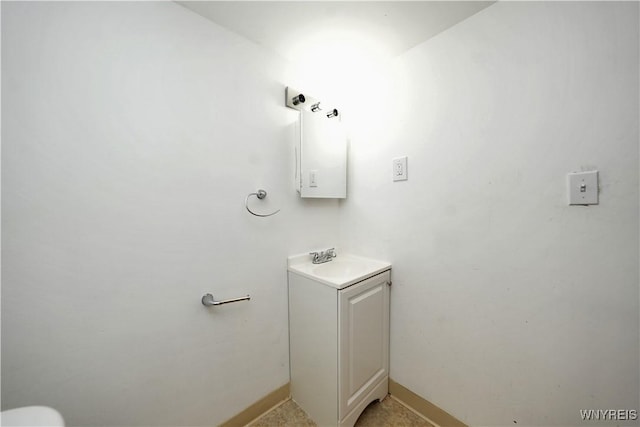 half bath with baseboards and vanity