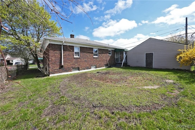 back of property featuring a lawn, brick siding, fence, and a chimney