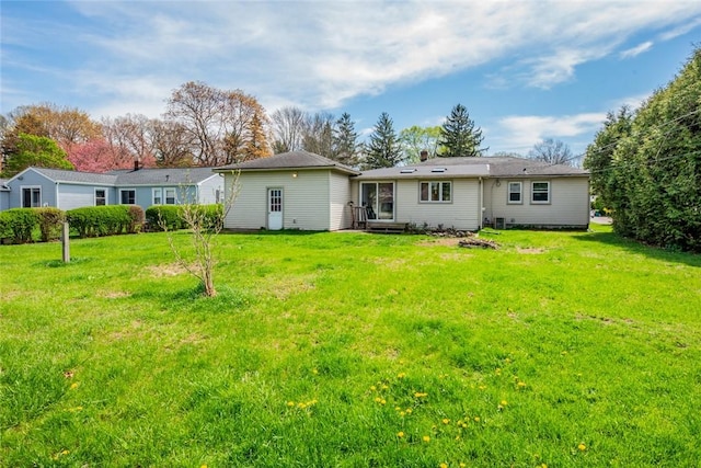rear view of property featuring entry steps and a yard