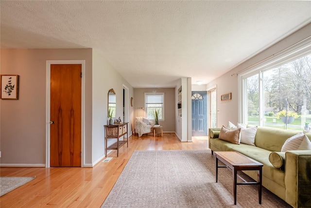 living area featuring baseboards, light wood finished floors, and a textured ceiling