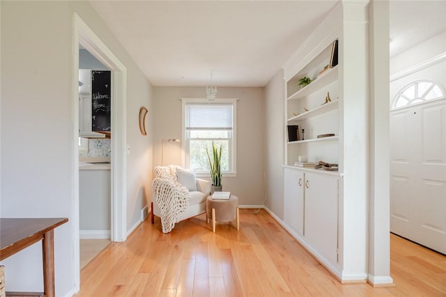 living area featuring baseboards and light wood finished floors