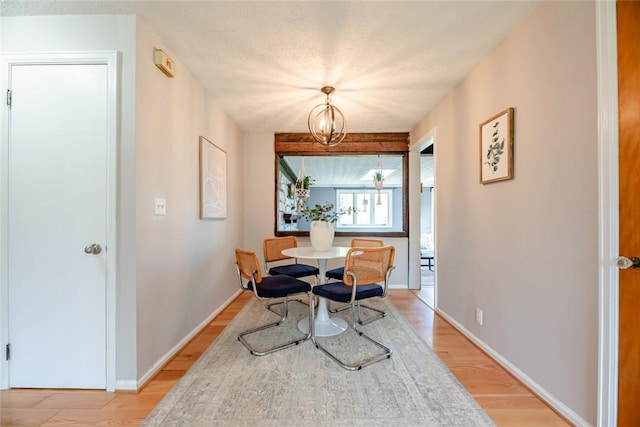dining space featuring baseboards, light wood finished floors, and a notable chandelier