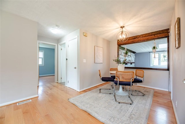 dining space with baseboards, a chandelier, wood finished floors, and visible vents