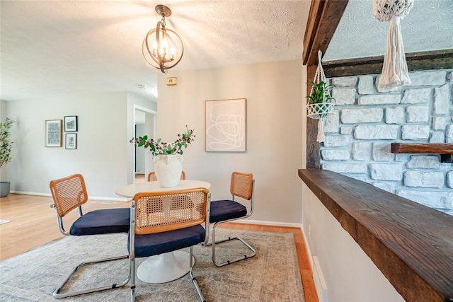 dining space featuring baseboards, a textured ceiling, and wood finished floors