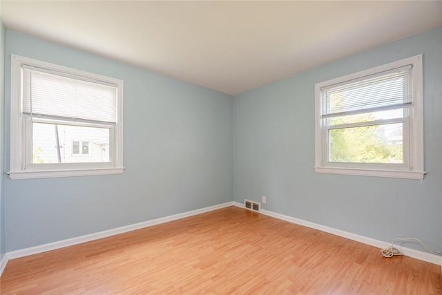 spare room with baseboards, visible vents, and light wood-style flooring