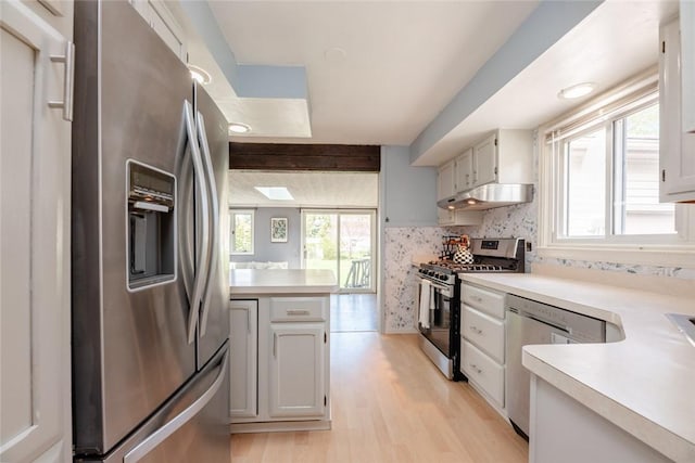 kitchen with light countertops, stainless steel appliances, under cabinet range hood, and light wood finished floors