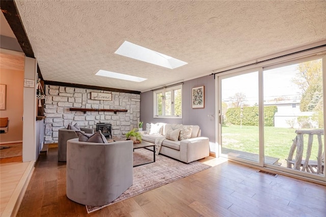 living area featuring a skylight, a textured ceiling, wood finished floors, and visible vents