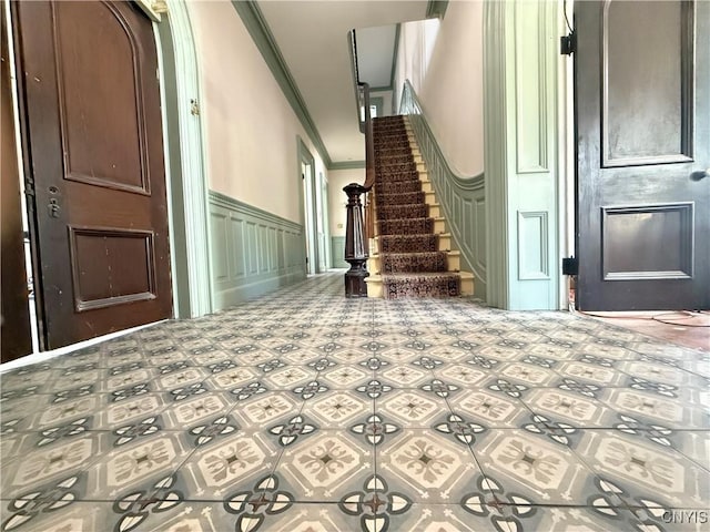 interior space featuring ornamental molding, stairs, a decorative wall, and wainscoting