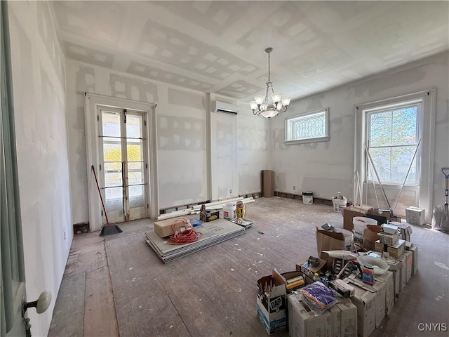 unfurnished dining area with wood-type flooring, an AC wall unit, and a notable chandelier