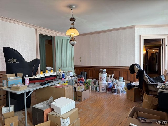 dining room with crown molding, wainscoting, hardwood / wood-style floors, and wallpapered walls