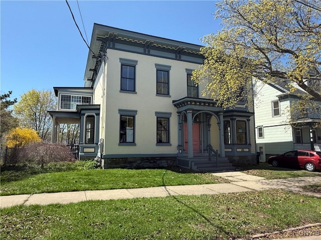 italianate-style house featuring a front lawn, stucco siding, and covered porch
