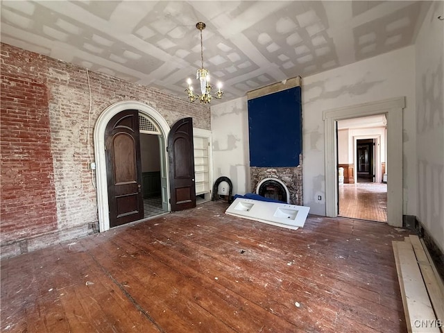 118 E 3rd St, Oswego, NY 13126 - unfurnished living room with wood-type flooring, a chandelier, a fireplace, arched walkways, and brick wall