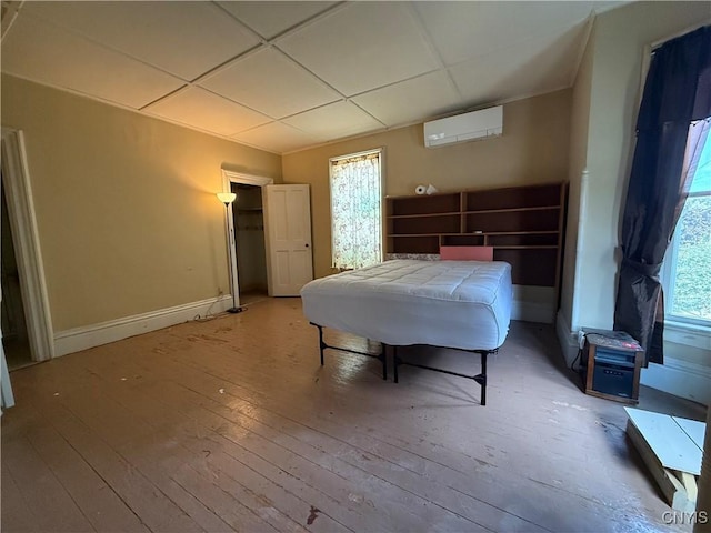 118 E 3rd St, Oswego, NY 13126 - bedroom featuring an AC wall unit, a drop ceiling, and light wood-style flooring