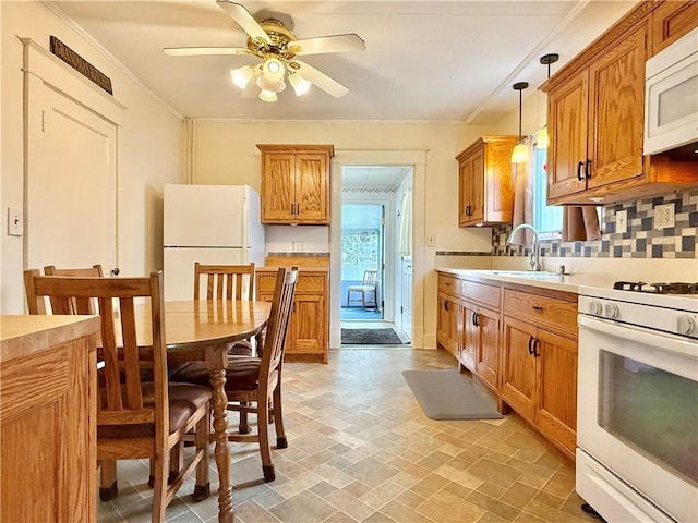 kitchen with brown cabinetry, decorative backsplash, white appliances, ceiling fan, and a sink