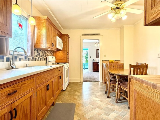 kitchen with crown molding, white appliances, ceiling fan, light countertops, and a sink